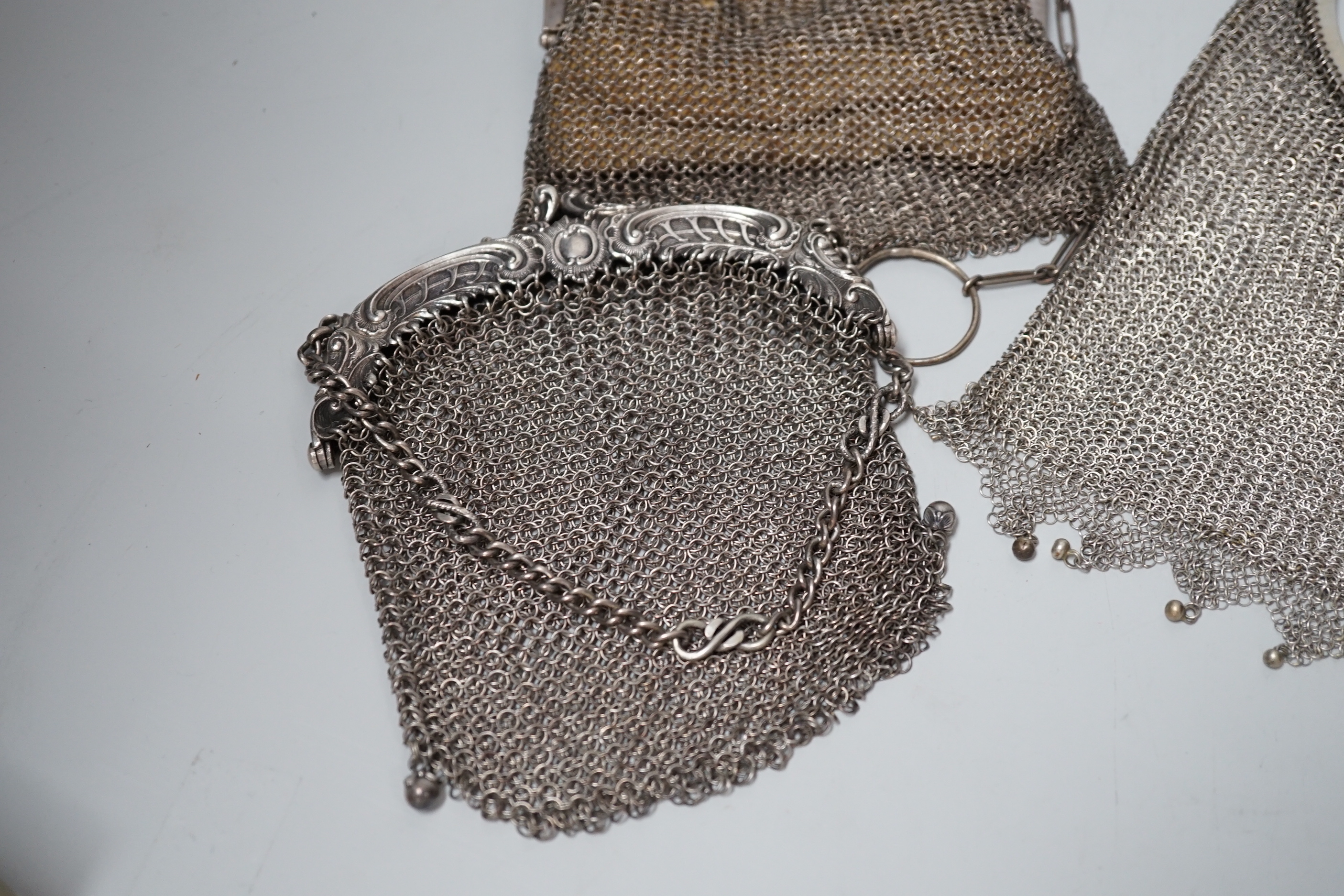 A George V silver gilt mesh evening bag, retailed by Mappin & Webb, Birmingham, 1916 and a smaller silver evening bag, a Chinese white metal mesh evening bag, maker LH and a German 900 standard white metal mesh evening b